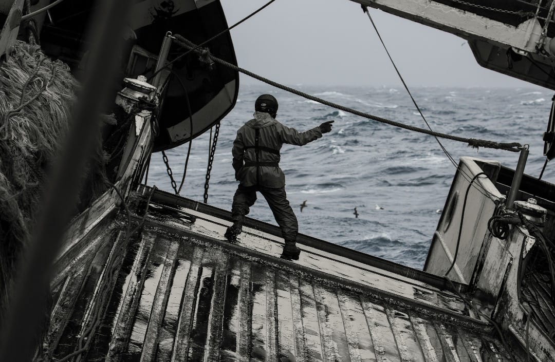A photo showing what could be a deep sea miner balancing on the deck of a large ship in choppy waters