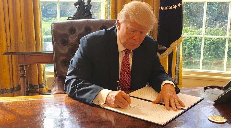 US president Donald Trump signing an executive order at the presidential desk in the Oval Office of the White House 